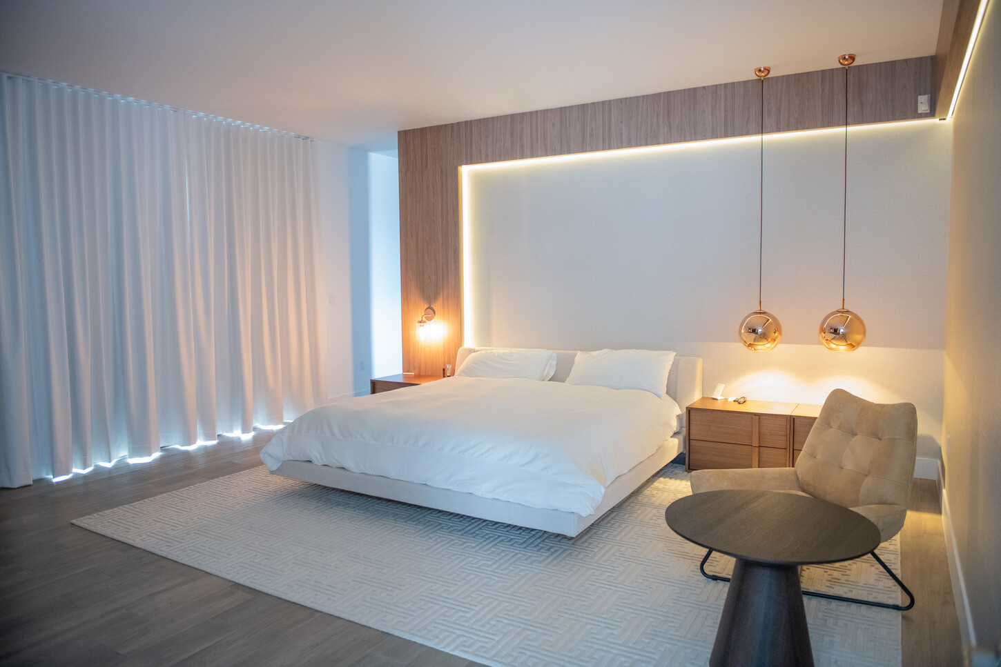 Wide view of primary bedroom with custom wood headboard and feature wall in Weston Botanico residence