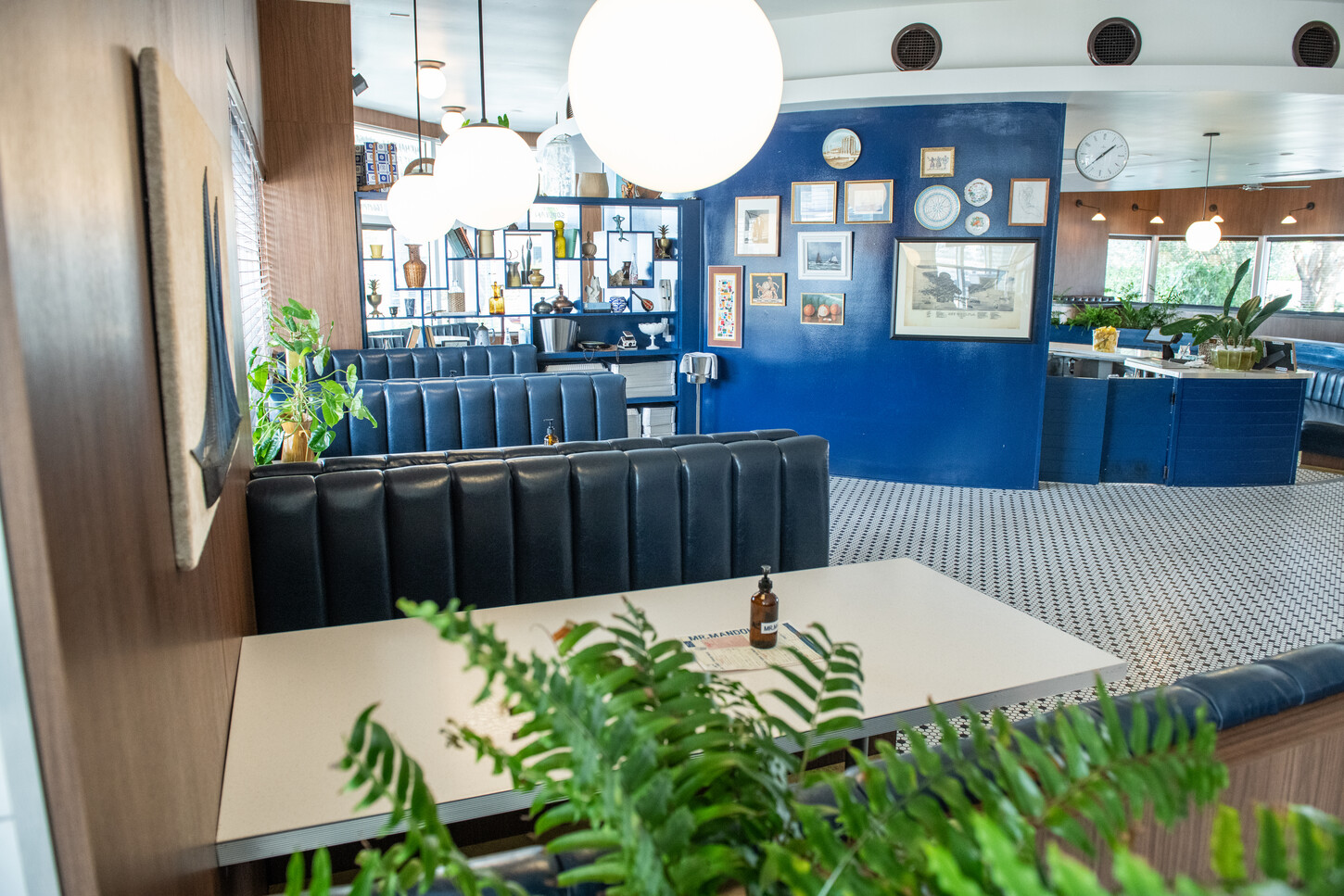 Black leather banquette seating with marble table against a blue accent wall