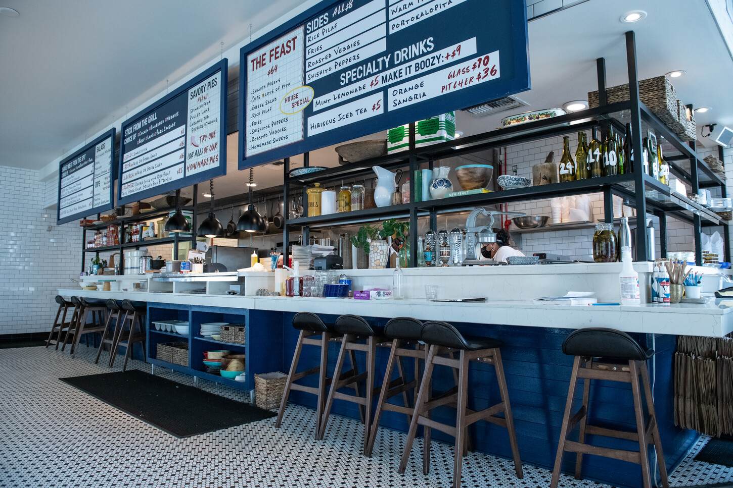 Black leather booth seating with globe lights, menu board, and bar view
