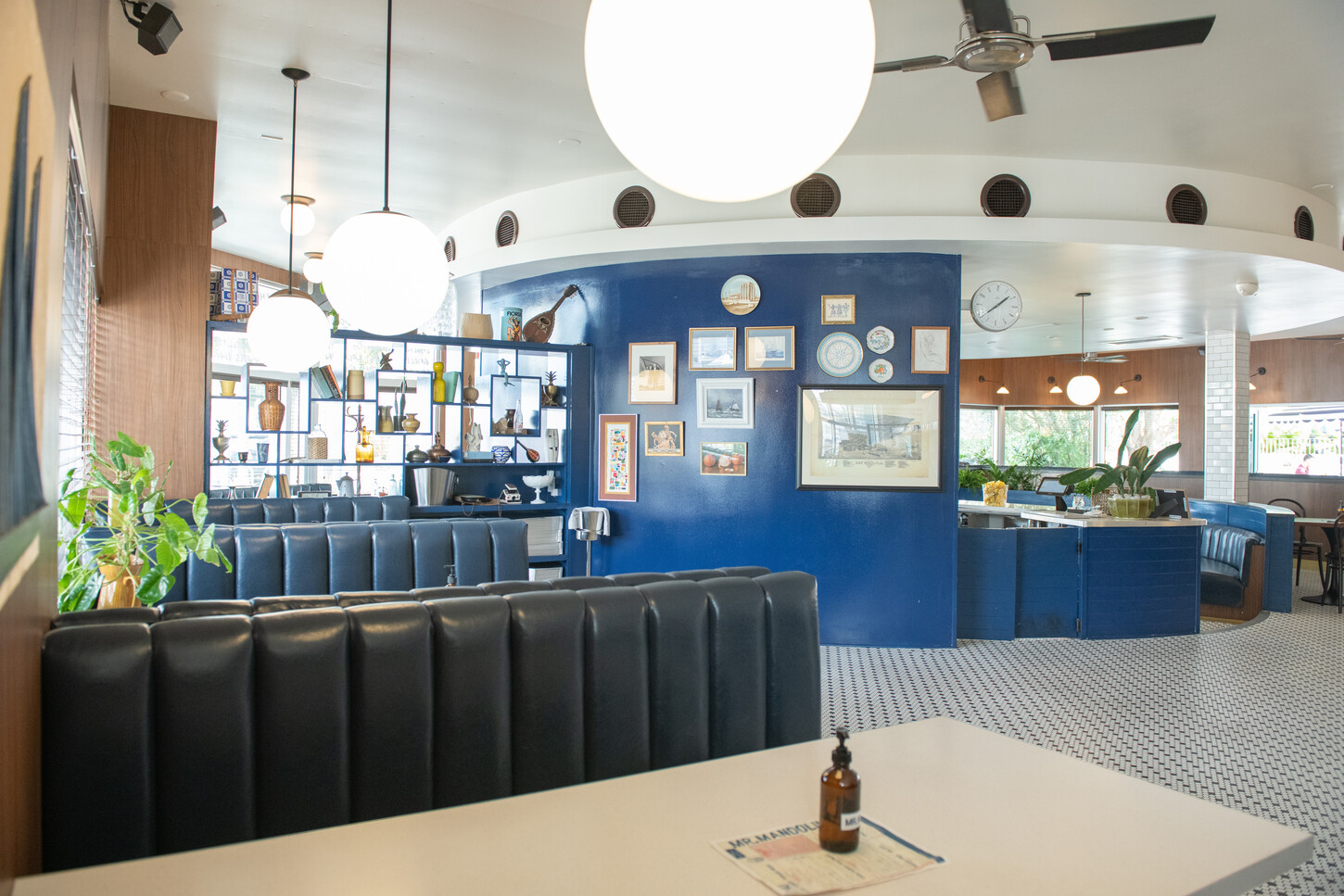 Black leather booth seating with marble table and menu board wall