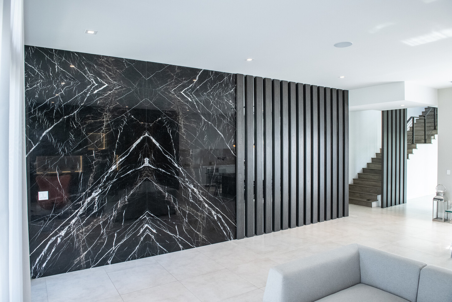 Custom black marble slab feature wall with integrated wood veneer and mirror divisions in Weston Botanico living room