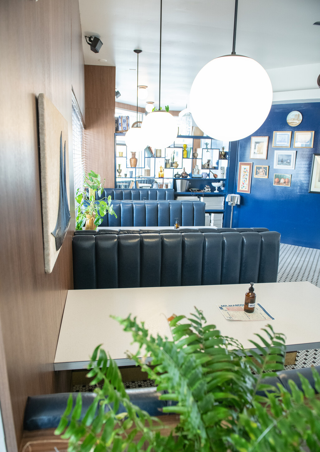 Blue accent wall with gallery frames above black booth seating