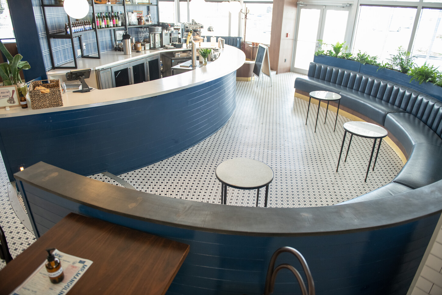 Blue channel-tufted corner booth seating with brass trim and tables