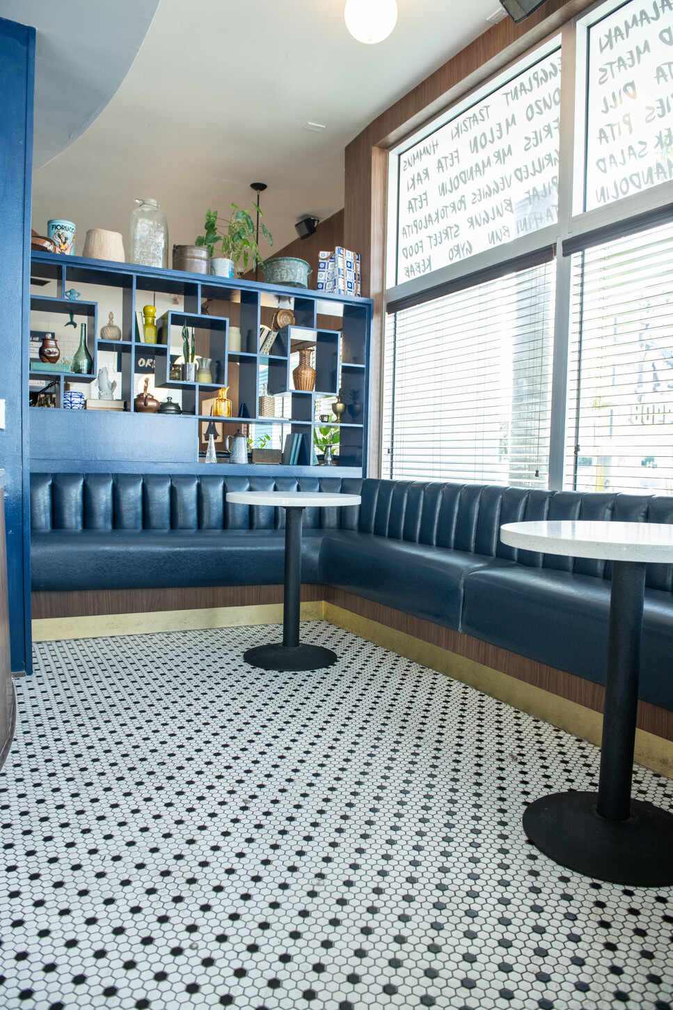 Blue curved booth seating with shelving and cafe table in the corner