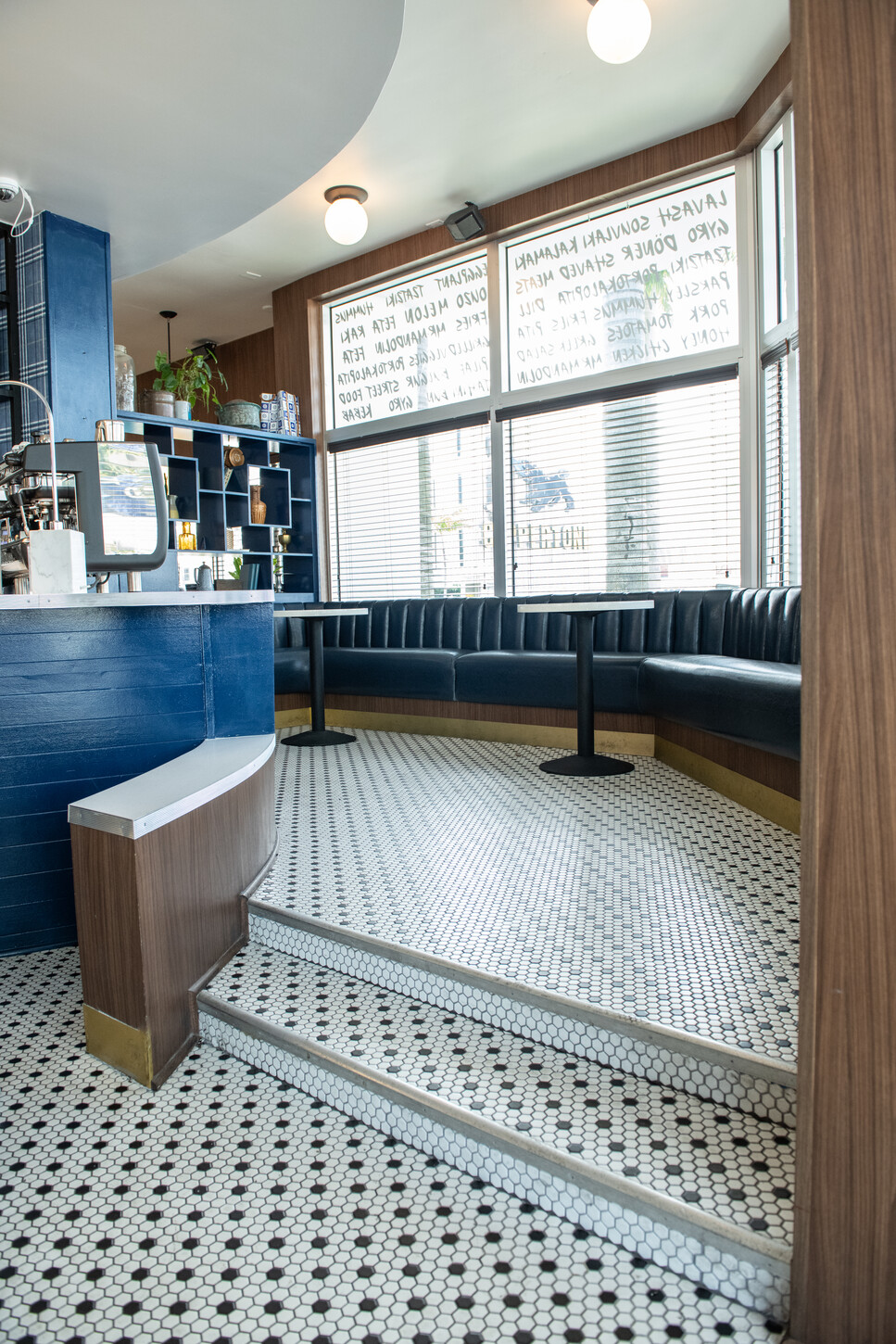 Blue curved booth seating with window light on a penny tile floor