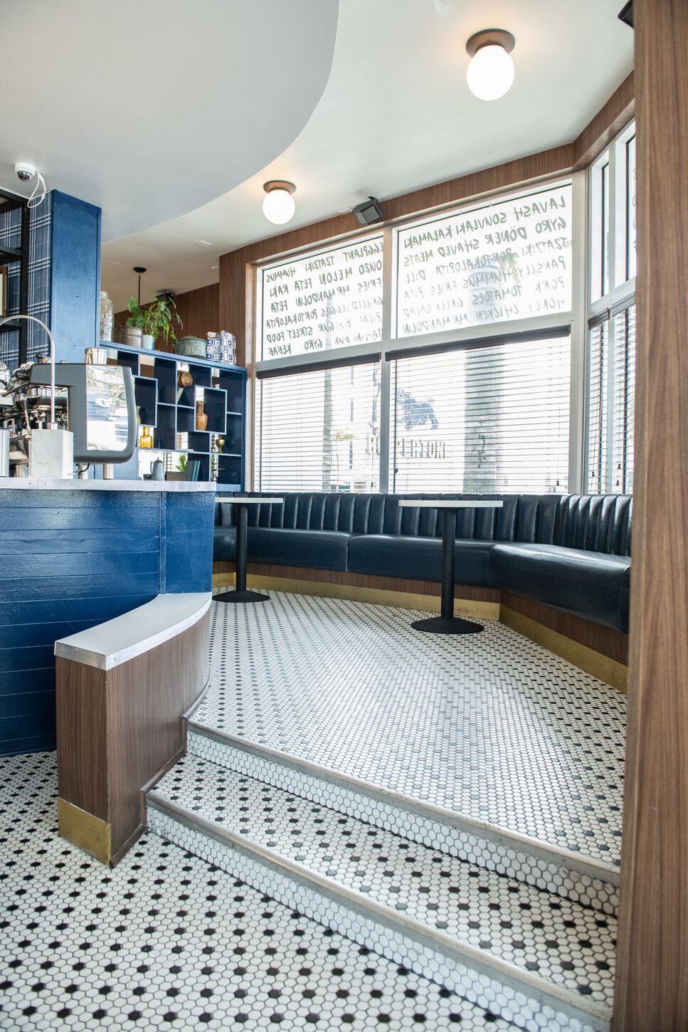 Blue curved booth seating with wood base on a white marble floor