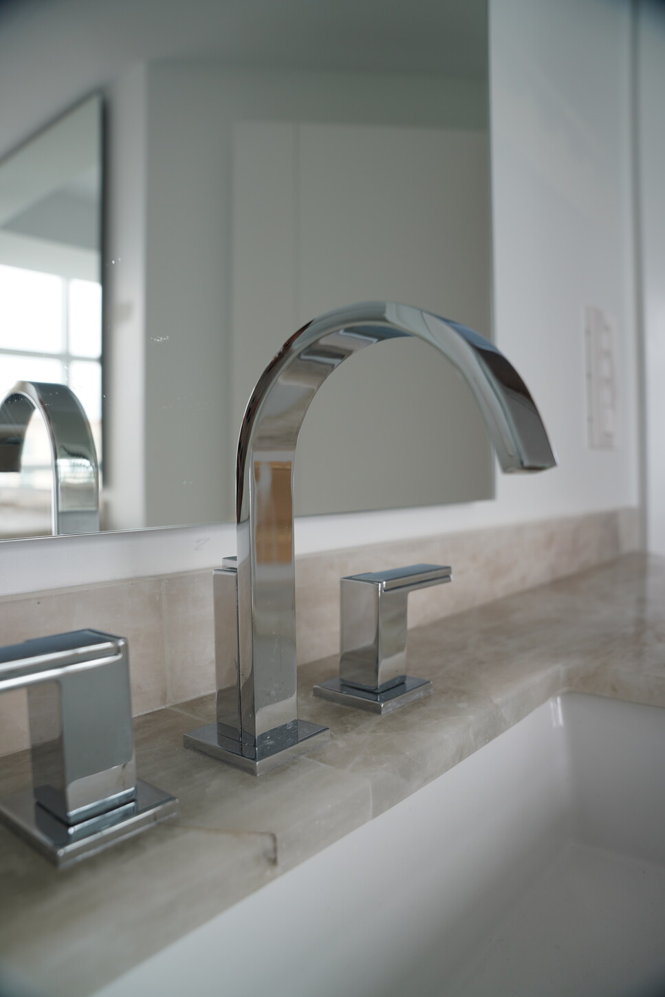 Widespread chrome bathroom faucet detail on a stone vanity