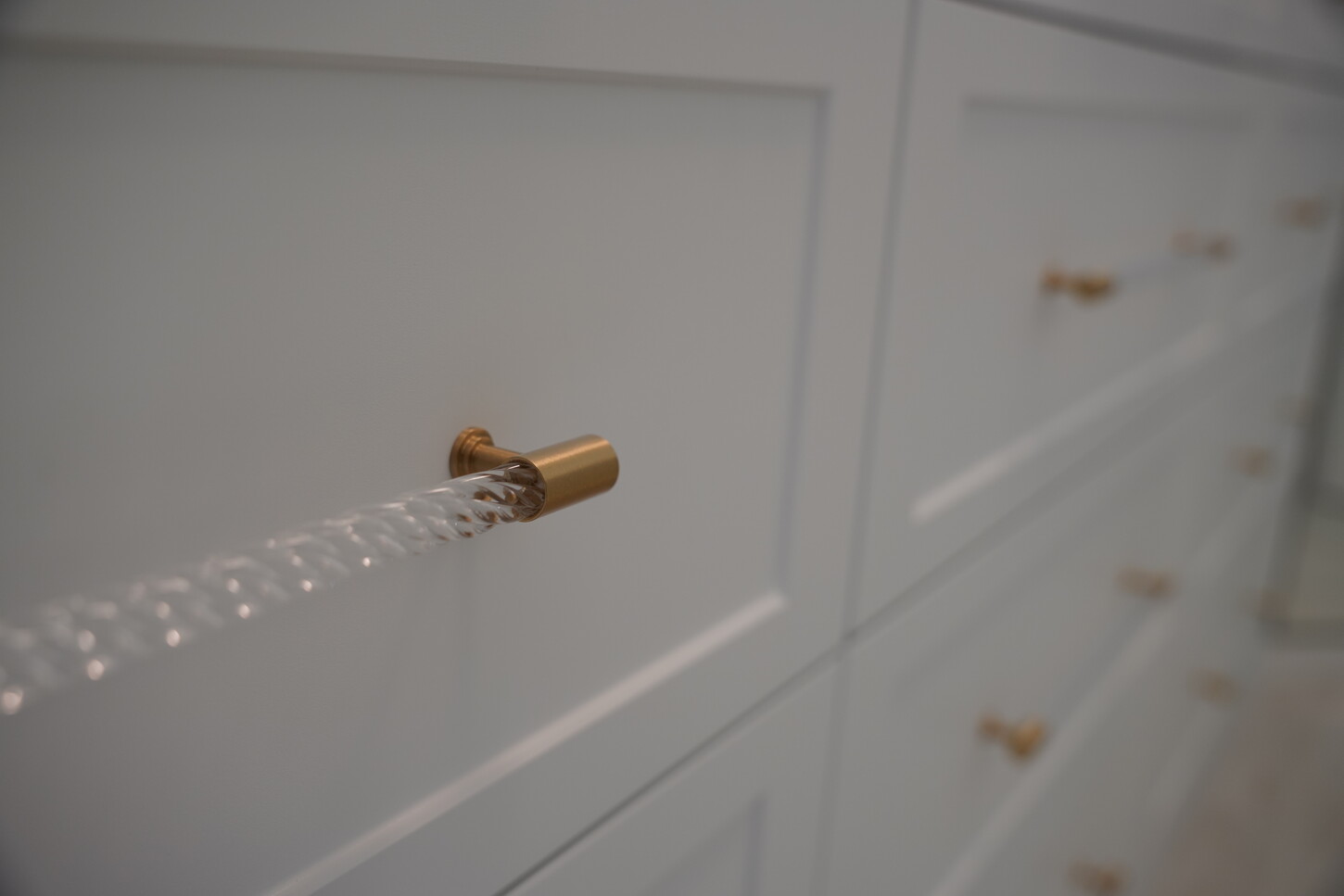 Custom shaker-style cabinetry with brass and fluted acrylic hardware pulls