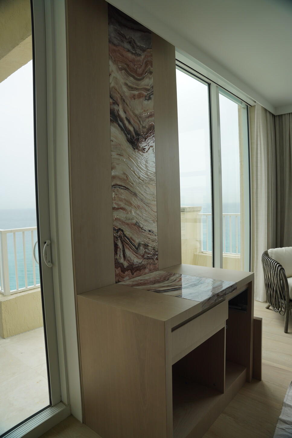 Custom floating desk with an imitation stone panel accent beside an ocean-view balcony door