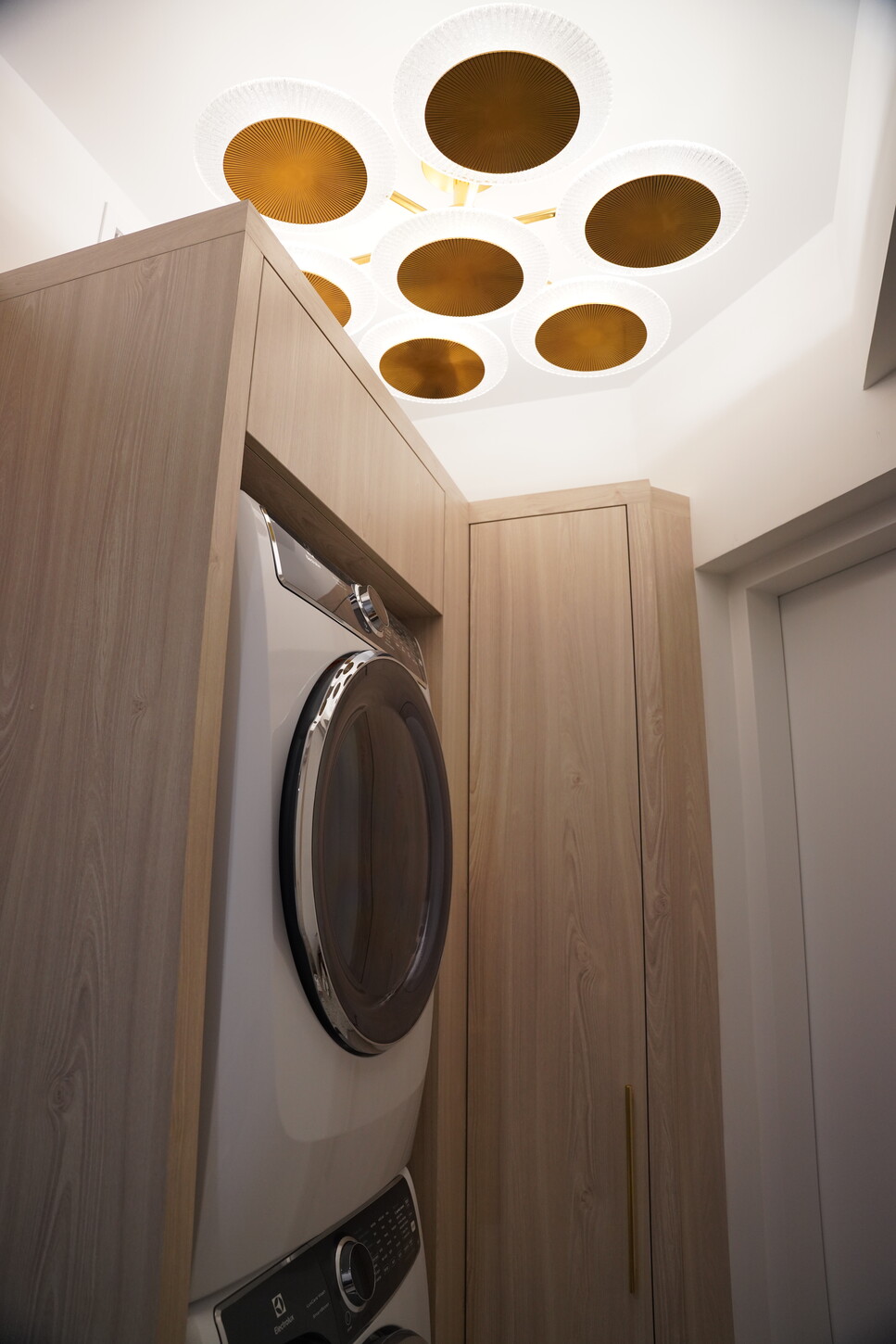 Custom laundry room cabinetry detail with a sculptural gold ceiling light overhead