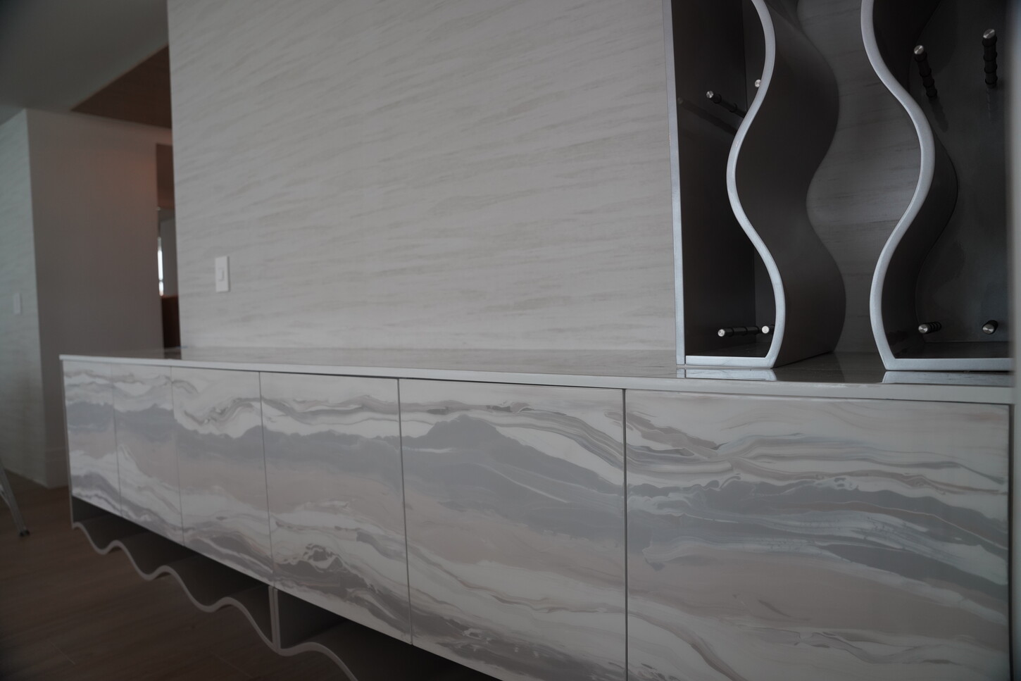 Custom media console wall unit with imitation stone cabinet fronts and a sculptural display niche