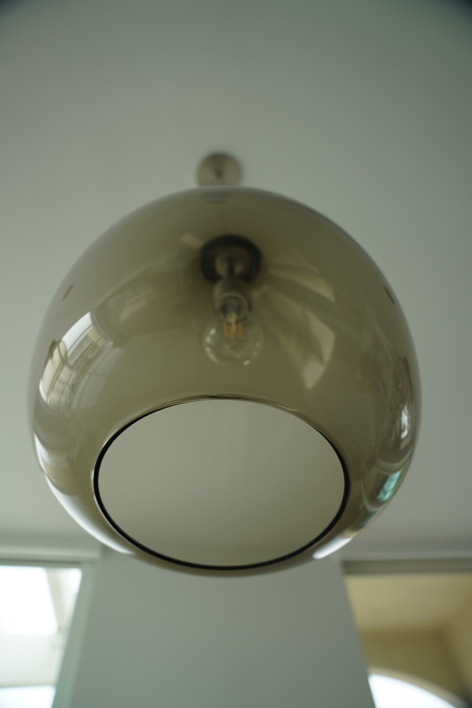 Smoked glass pendant light detail with an exposed filament bulb
