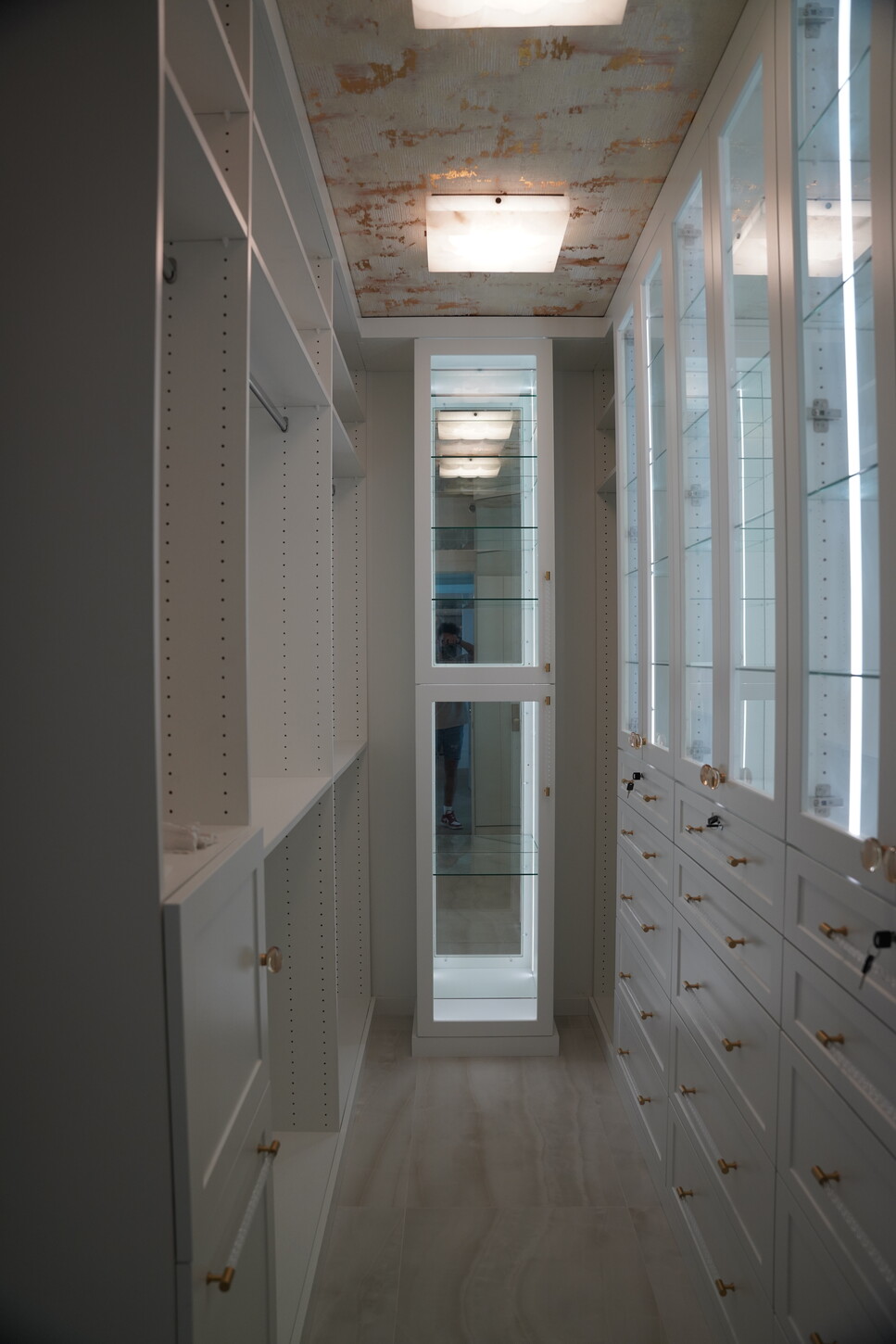 Custom walk-in closet with white shaker-style cabinetry and a full-length mirror