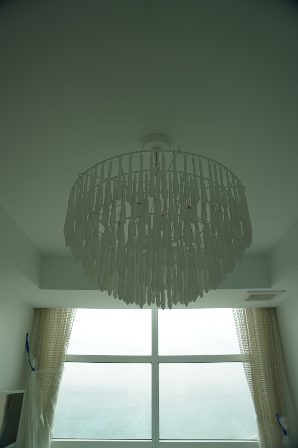 Woven fringe chandelier over an ocean-view bedroom window