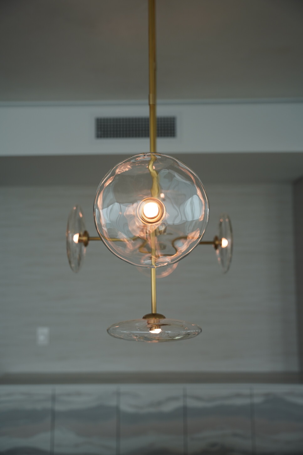 Sculptural glass-disc pendant fixture over a wood-paneled living space