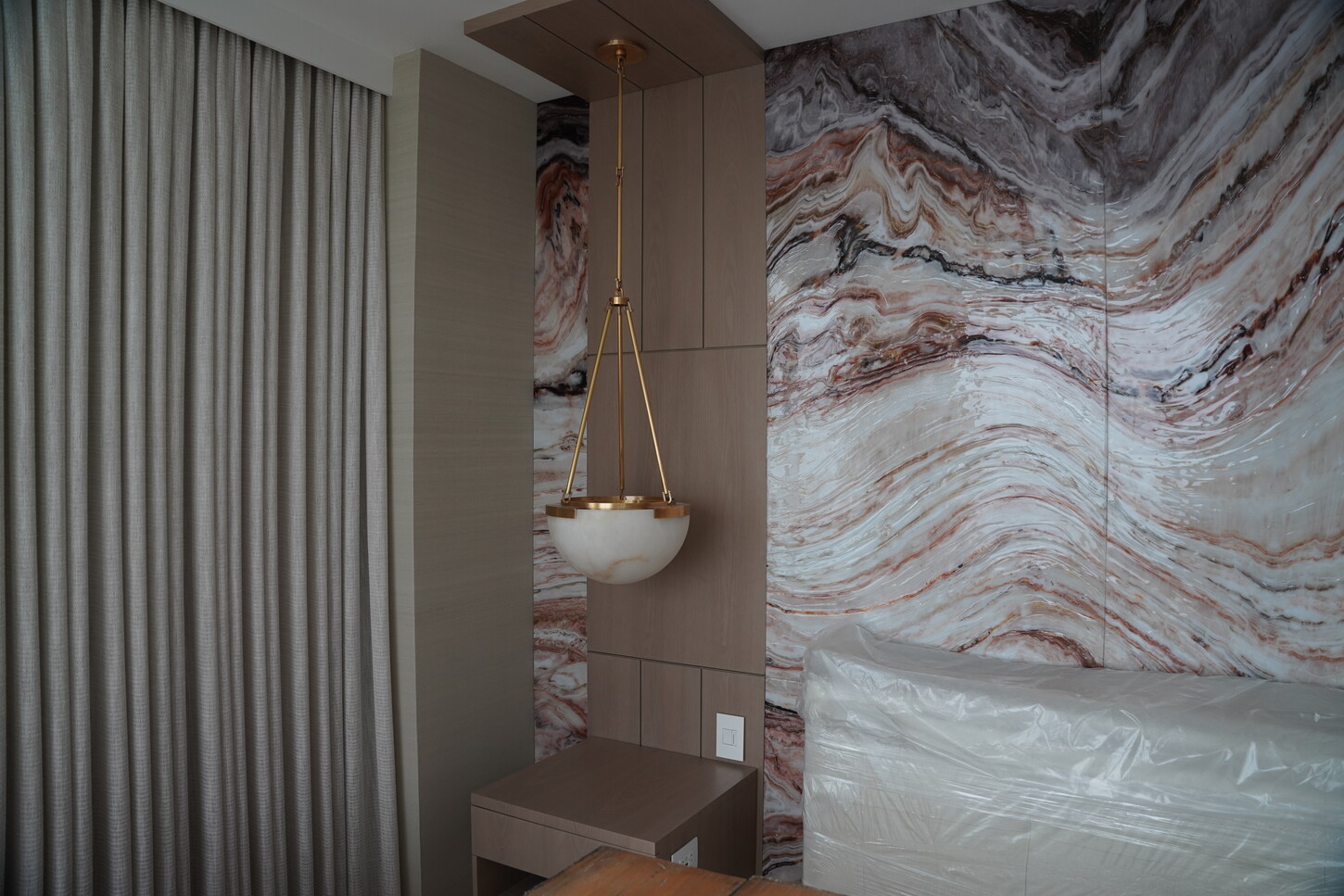 Headboard feature wall with epoxy-finished imitation stone panels and an alabaster pendant light in a Boca Raton primary bedroom