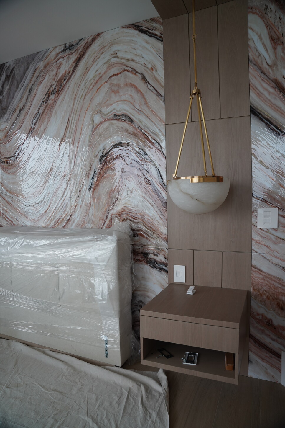 Master bedroom renovation featuring a custom headboard feature wall and brass pendant lighting