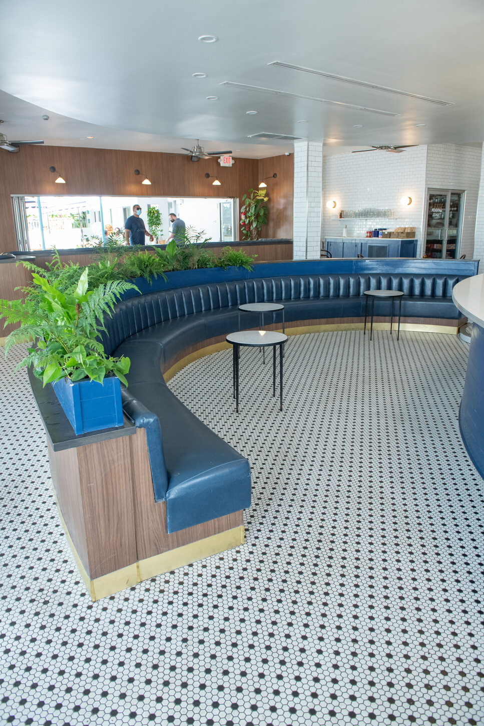 Curved blue bar with brass trim detail on a penny tile floor