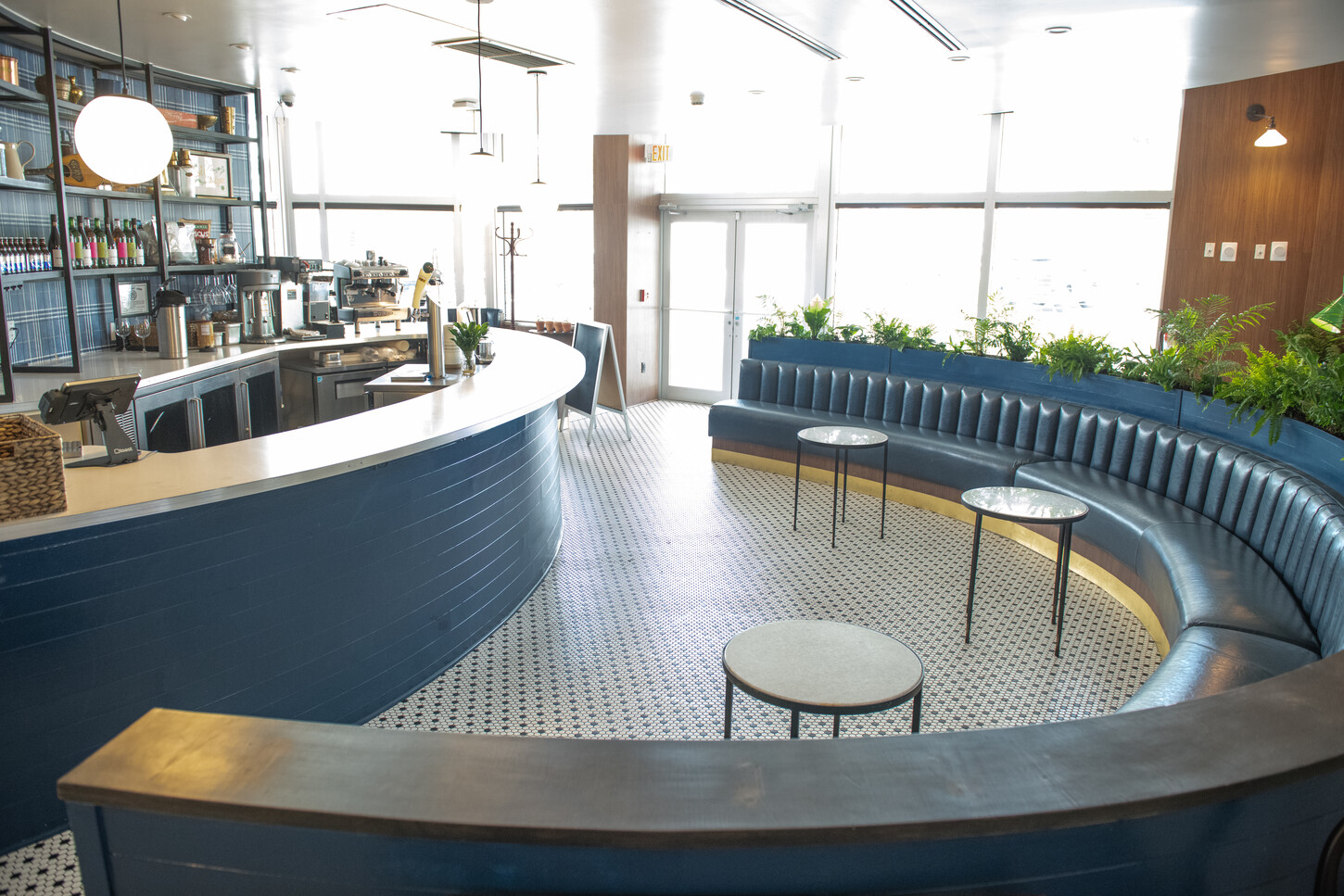 Curved blue bar with standing tables in an open floor plan