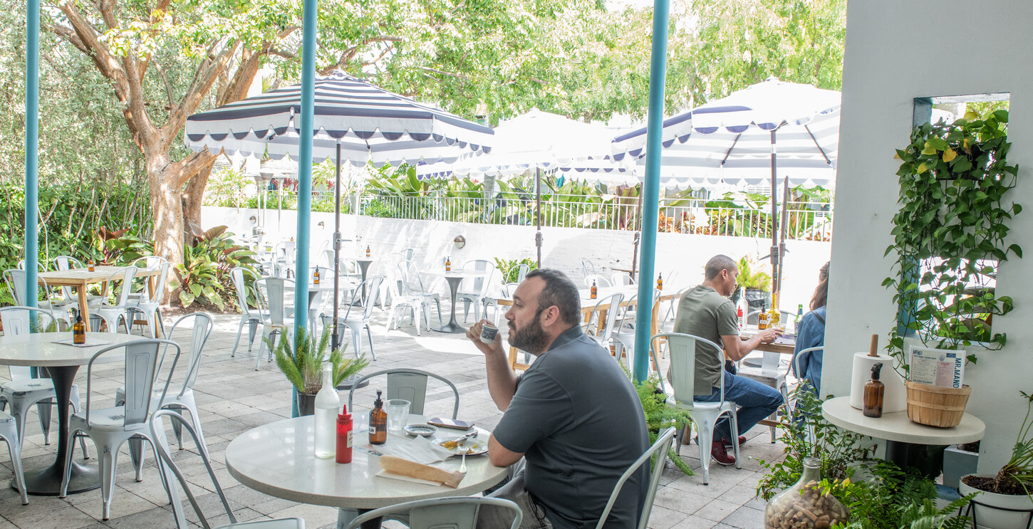 Dark wood booth seating with a patio view through open doors and bistro chairs