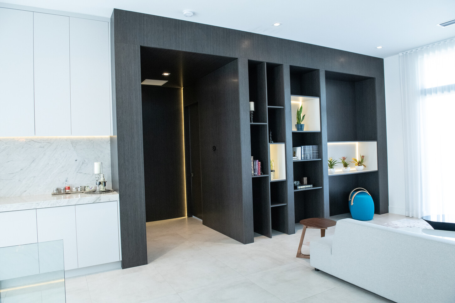 Dark wood built-in living room cabinets with integrated LED feature lighting in Weston Botanico residence