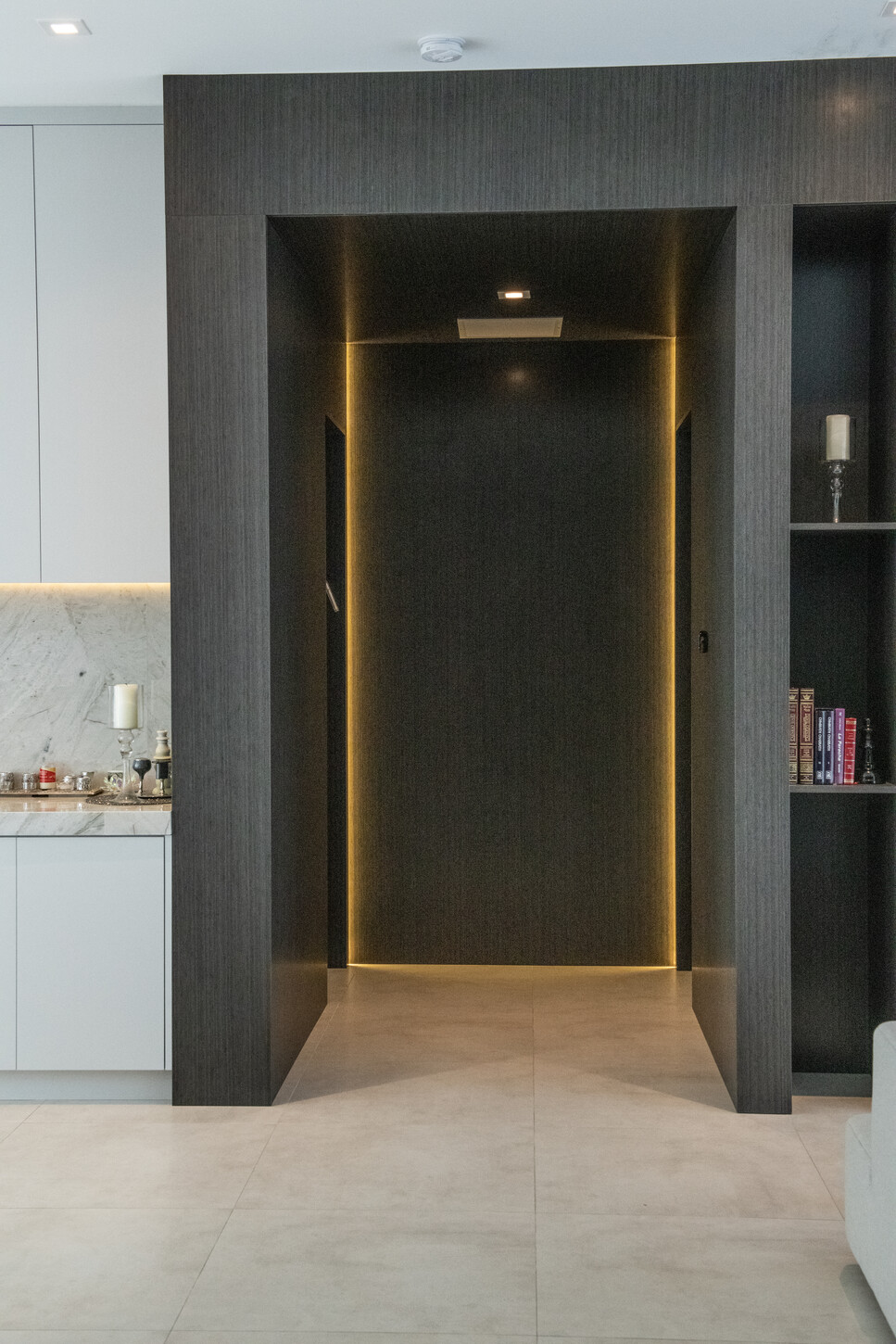 Dark wood pivot door in a Weston Botanico hallway finished with matching veneer grain and gold trim detailing