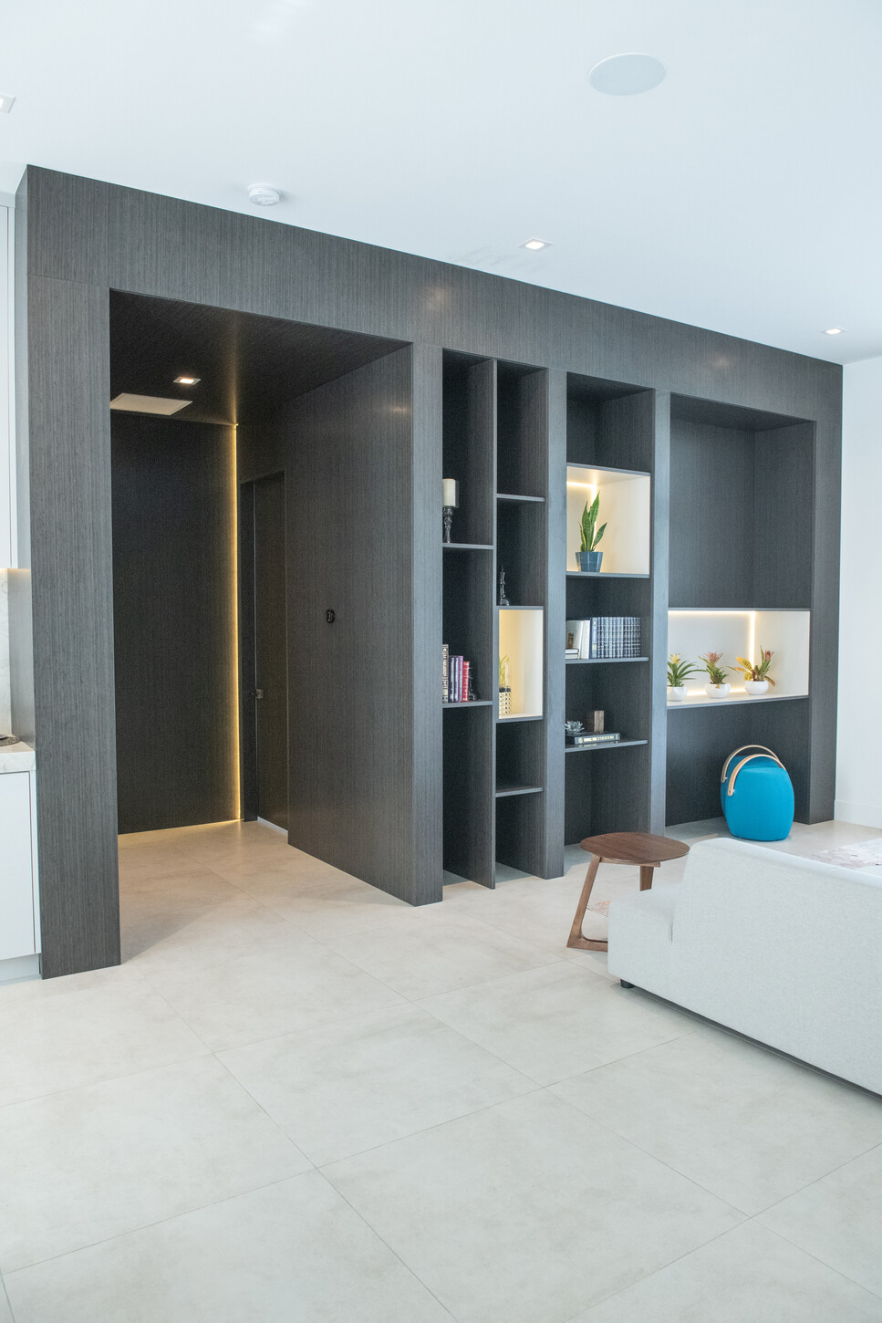 Flush wood veneer pivot door shown open along a custom-paneled hallway in a Weston Botanico residence