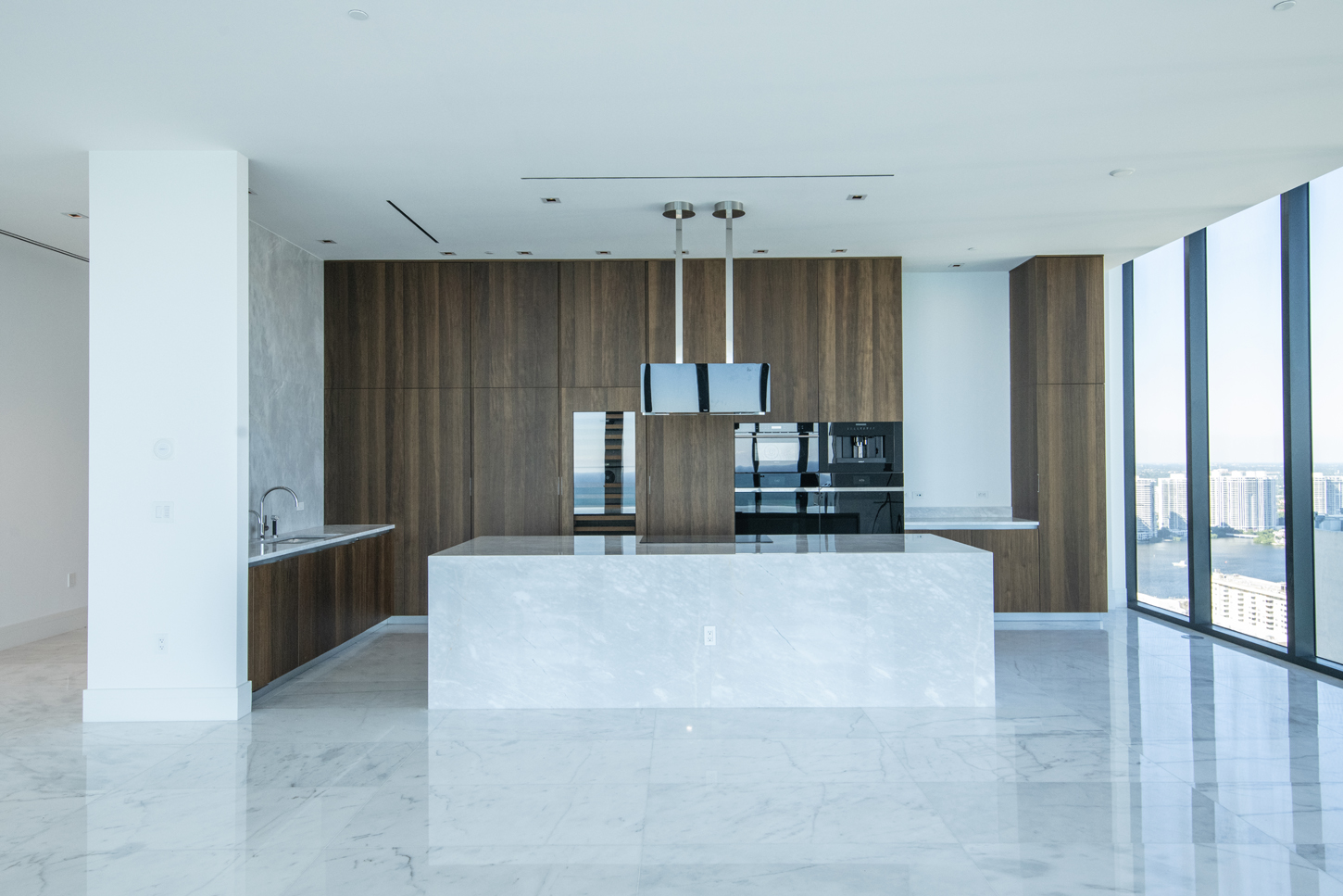 Modern high-rise kitchen with marble island and panoramic waterfront views, designed by CM Custom Design in Miami