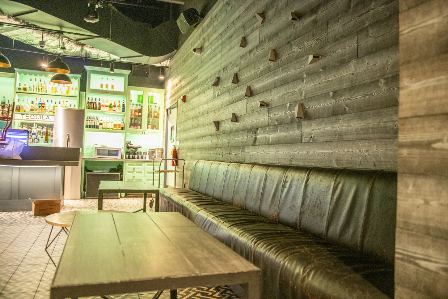 Speakeasy-style cocktail lounge renovation with custom green millwork and bar shelving by CM Custom Design
