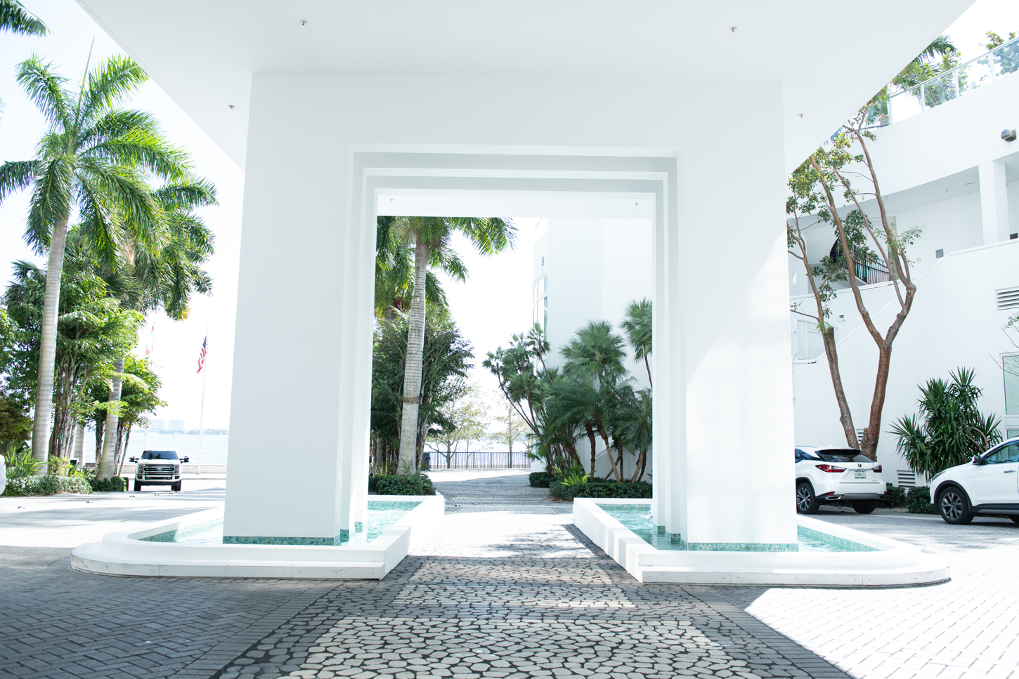 Modern hospitality building lobby entrance with reflecting pools and landscaping by CM Custom Design in Miami