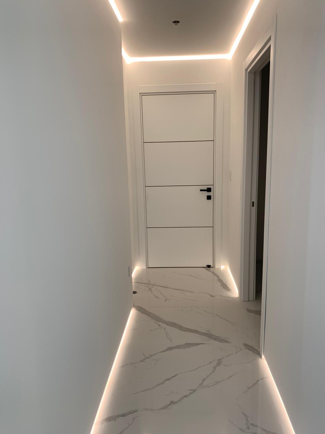 Walk-in shower with a black rain shower head and illuminated tile niche