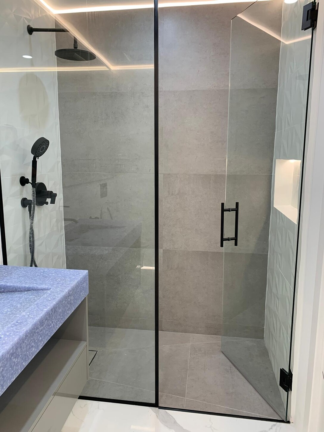 Bathroom vanity with terrazzo countertop, matte black fixtures, and integrated LED lighting