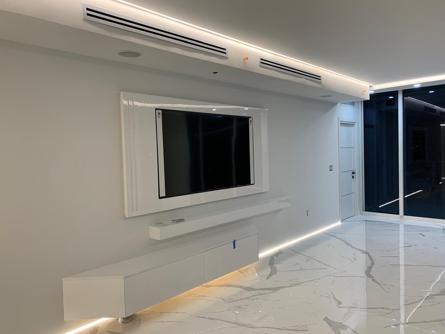 Custom kitchen cabinetry with built-in cooktop and subway tile backsplash at night