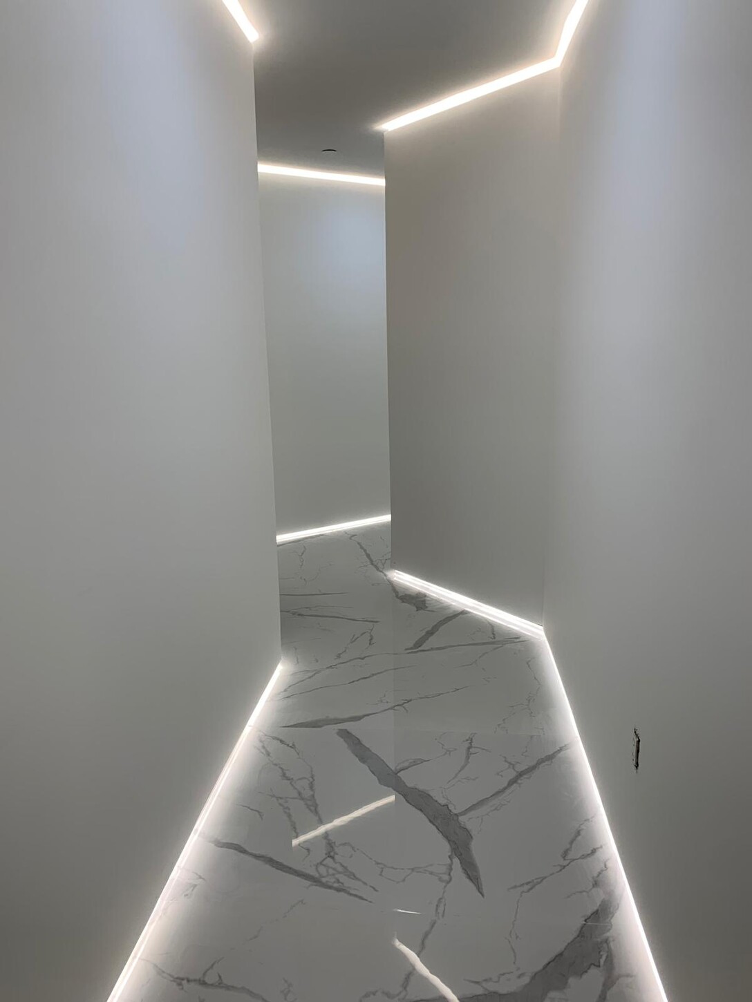 Transition from the kitchen into the hallway, with the floating media wall visible