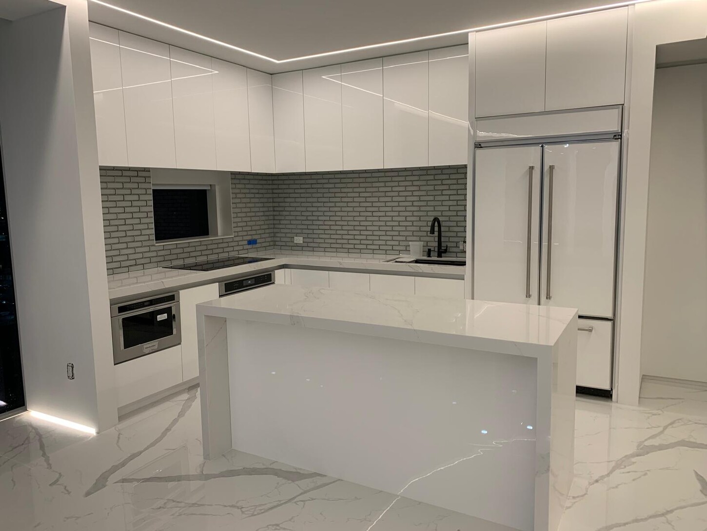 Custom kitchen with a waterfall-edge island and book-matched marble flooring in a Midtown Miami waterfront residence