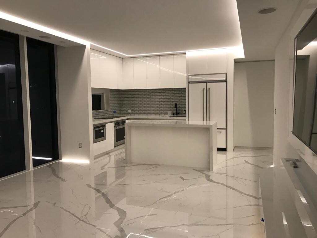 Living room and kitchen with curved floor-to-ceiling windows at night in this Midtown waterfront residence