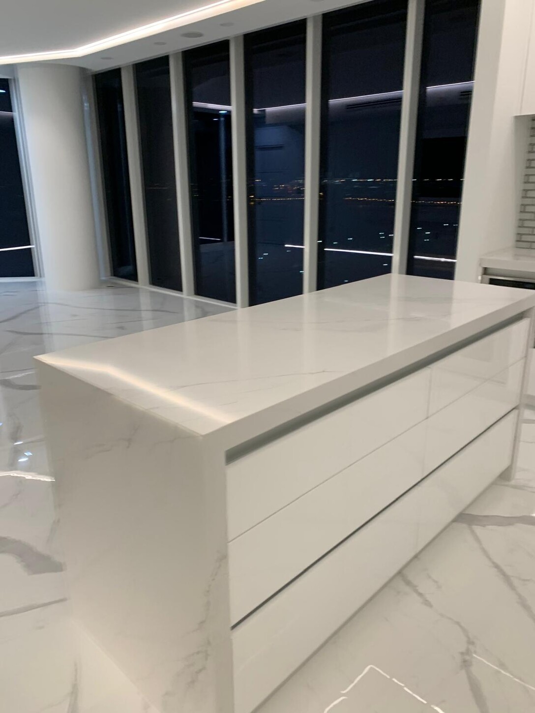 Living room and kitchen with book-matched marble flooring at night