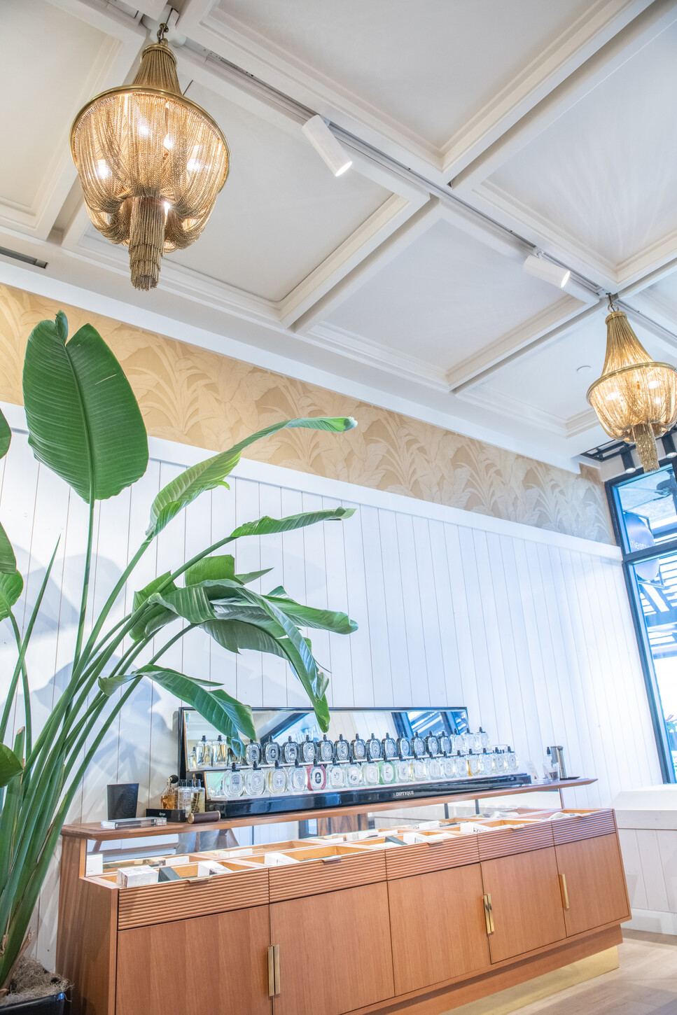 Detail of brass chandelier and coffered ceiling above a custom retail fragrance counter in a Diptyque boutique