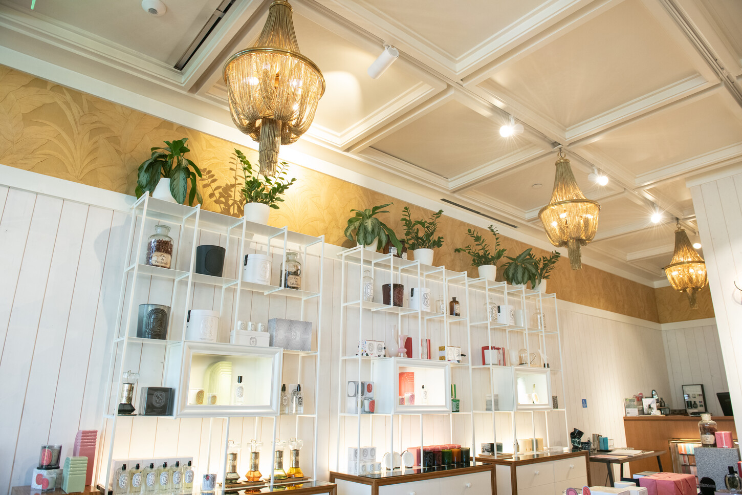 Handcrafted coffered ceiling moldings with brass chandeliers in a luxury retail boutique