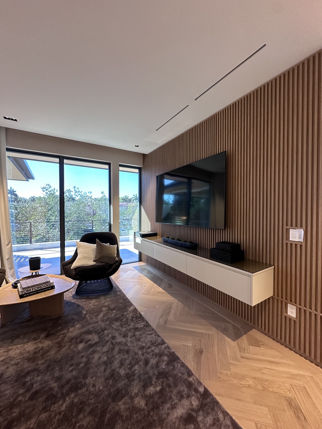 Wide view of the wood-slat TV wall and floating console in a Coral Gables living room