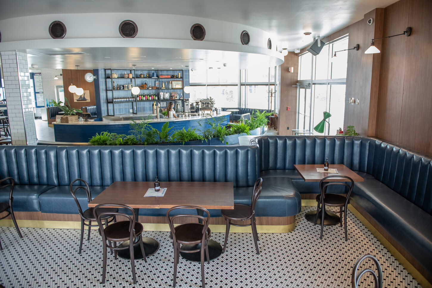 Wide view of round skylight, ceiling fans, and blue planter booth seating