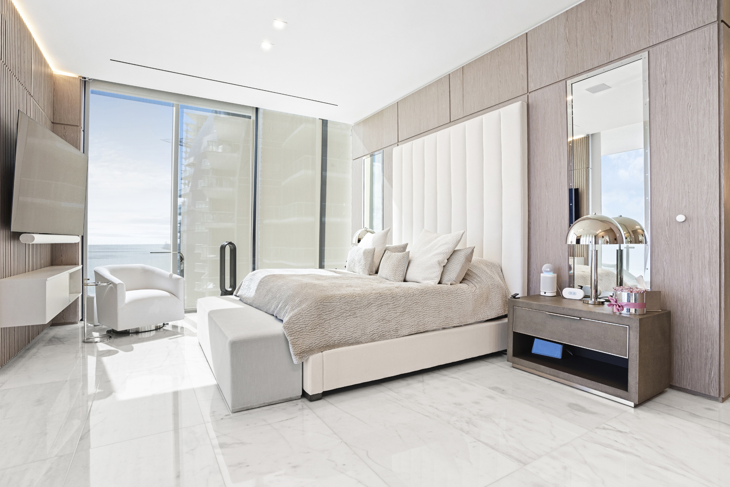 Primary bedroom with custom oak wall paneling and ocean-view balcony