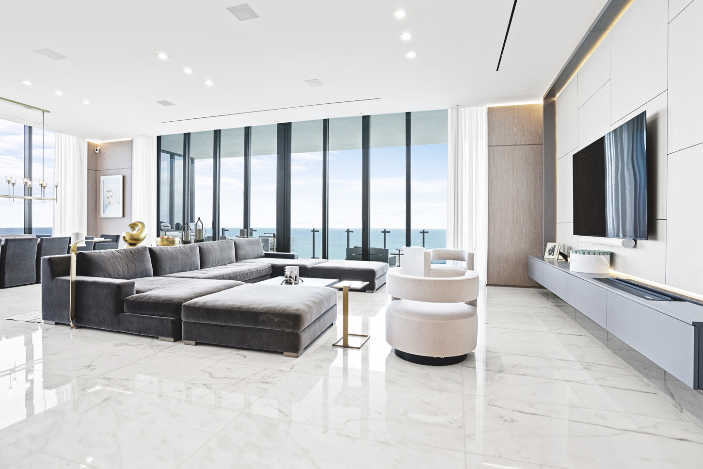 Living room with custom media wall, wood paneling, and ocean view in luxury Sunny Isles residence