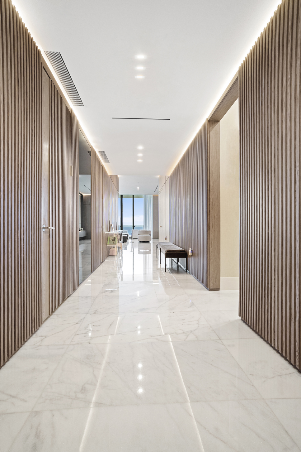 Entry hallway with custom wood paneling leading to ocean-view living space