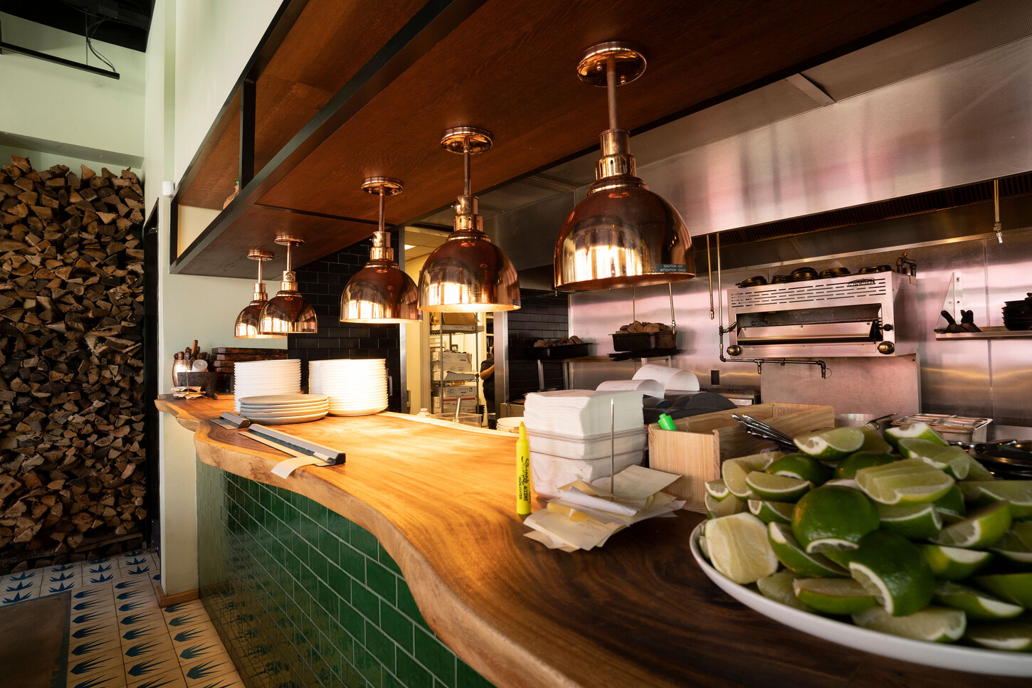 Live-edge wood counter with green tile and copper pendant lights at Bakan Wynwood in Miami