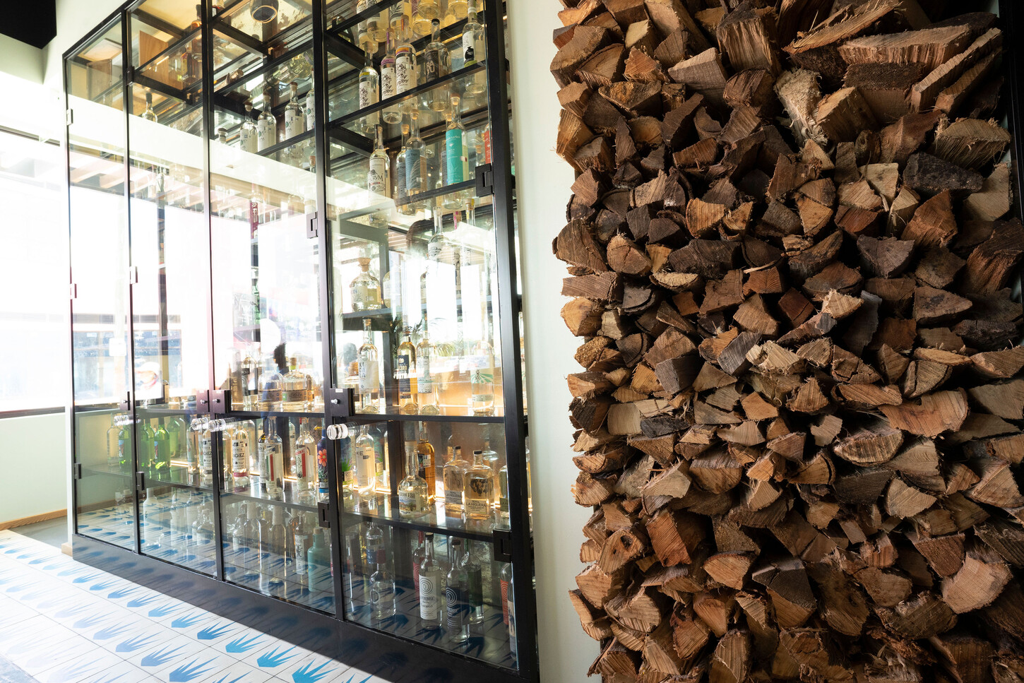 Detail of a firewood wall and steel and glass cabinet at Bakan Wynwood restaurant in Miami