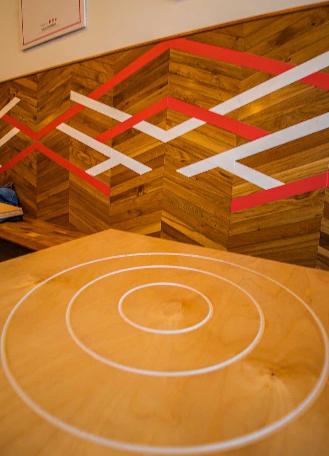Chevron wood accent wall with red and white lines above a table with circle inlay in Wynwood, Miami