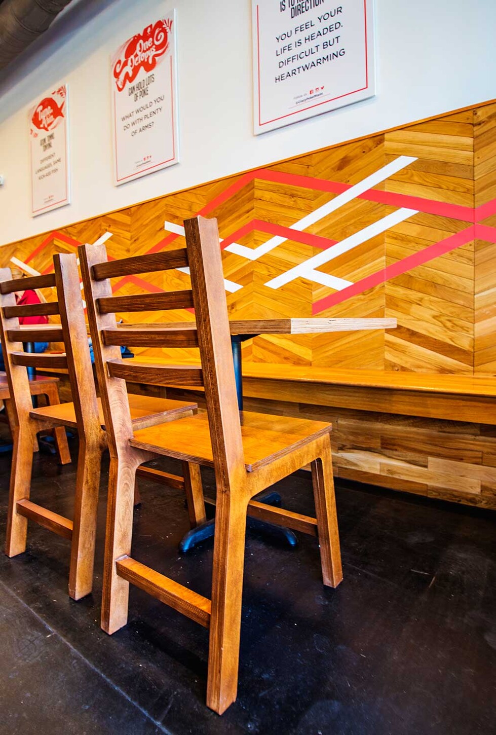 Custom ladder-back wood chairs in front of a chevron accent wall in a Wynwood restaurant