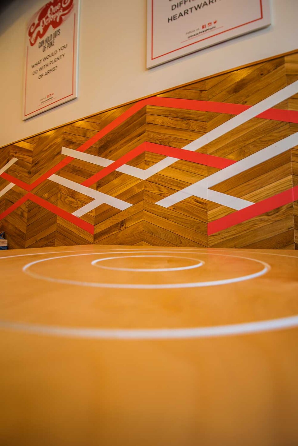Custom wood table with white circle inlay in front of a chevron wood accent wall in Wynwood, Miami