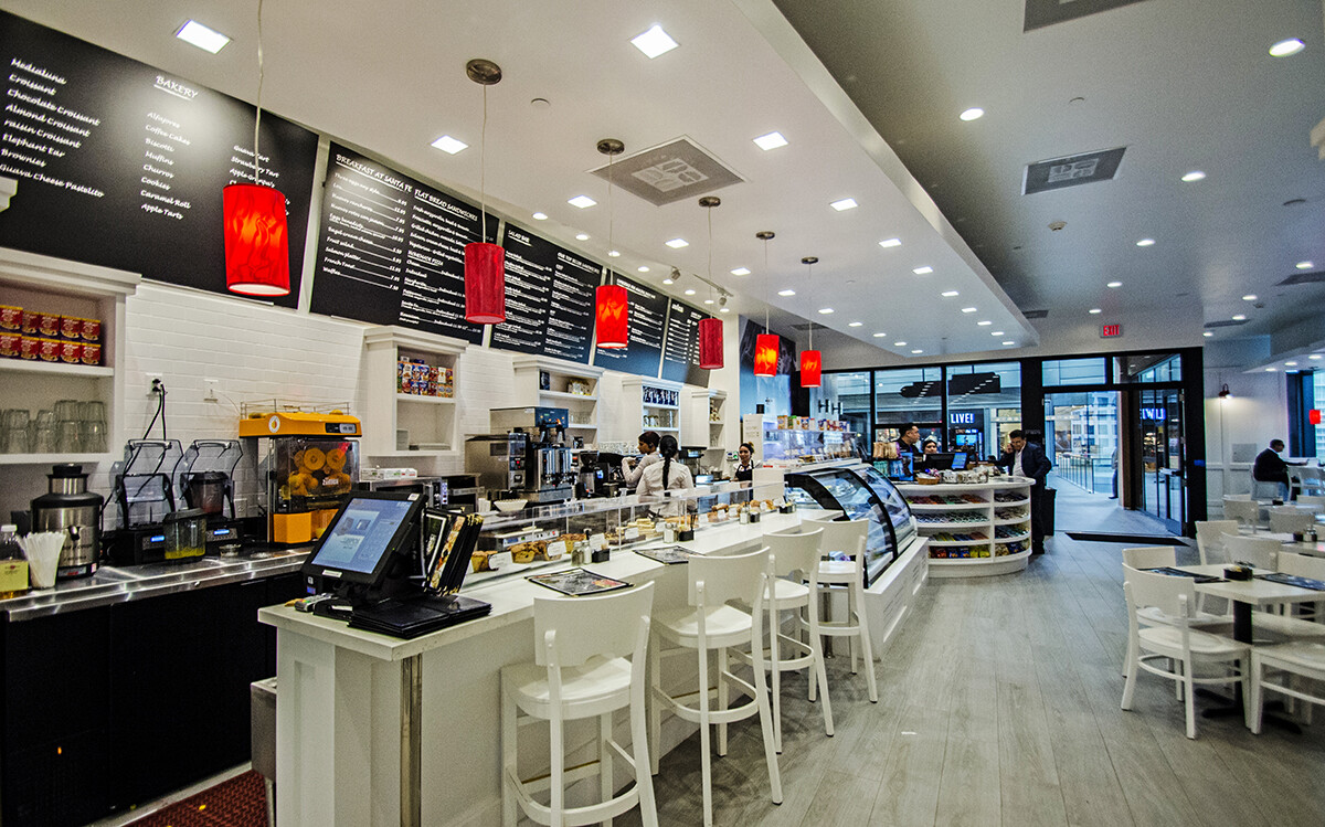 Custom millwork Brickell coffee shop build-out by CM Custom Design with coffee bar, white bar stools, and menu boards in Miami